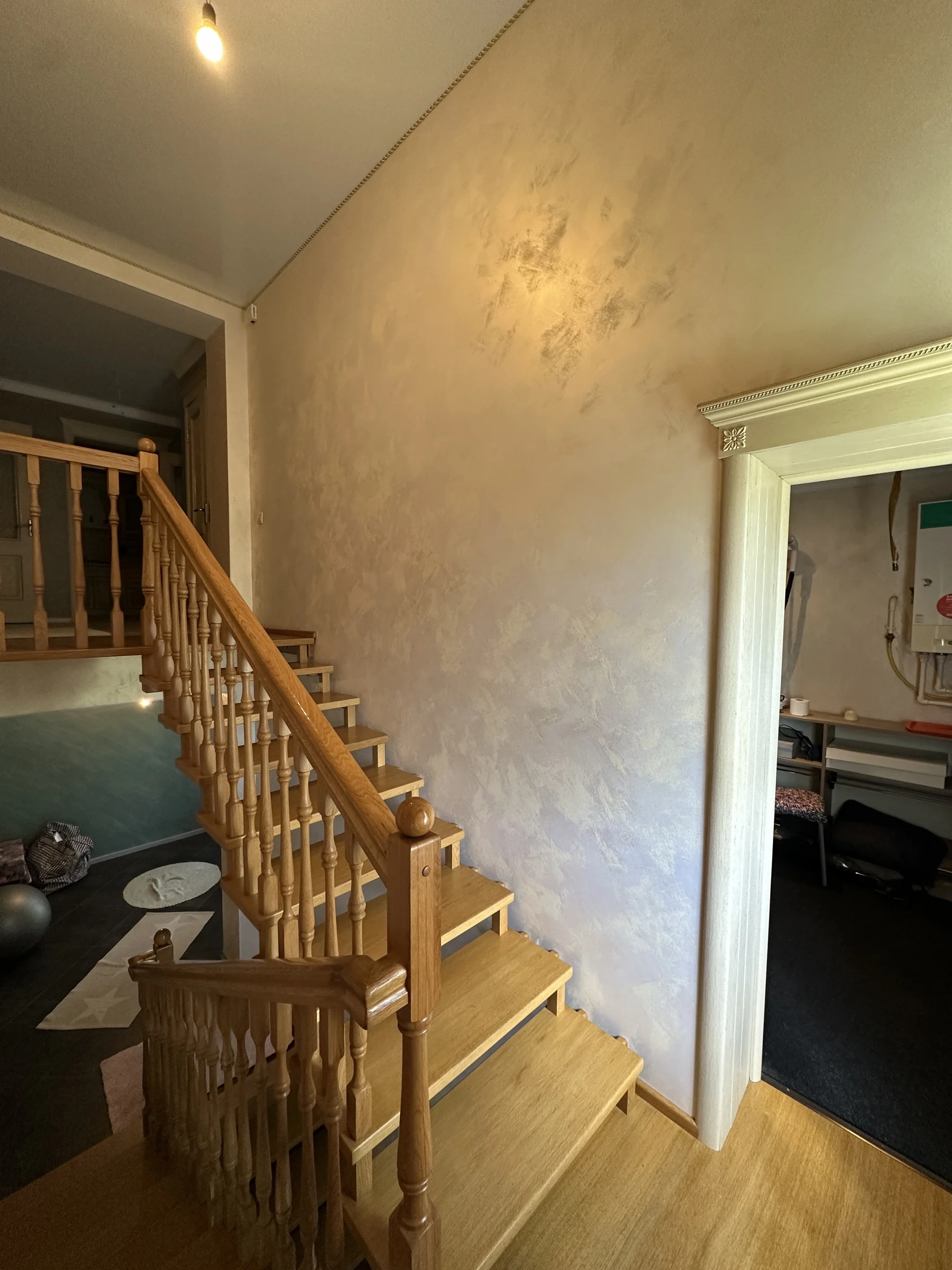 Timber staircase beside a softly textured decorative wall