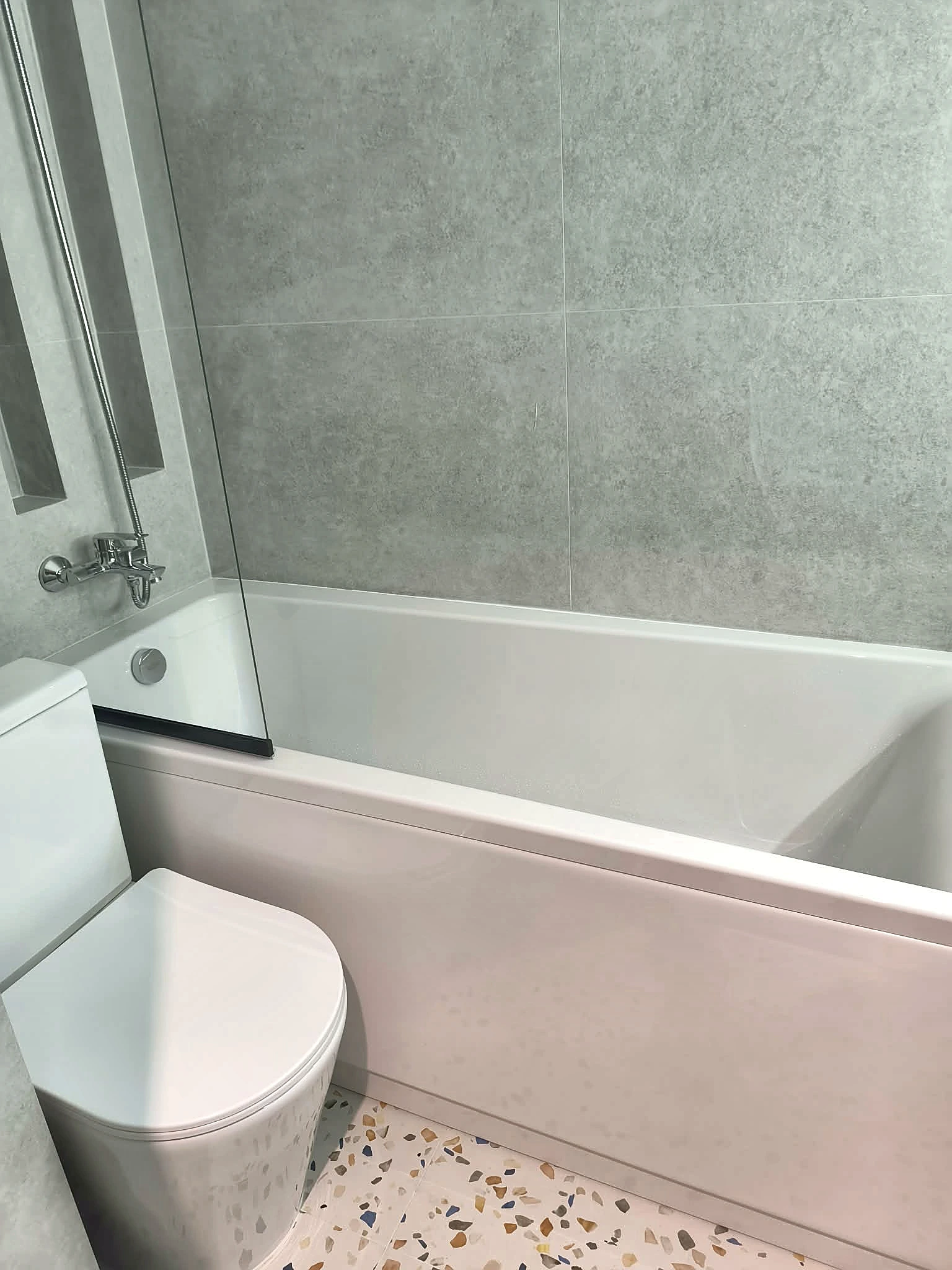 Bath installation with large wall tiles and terrazzo floor