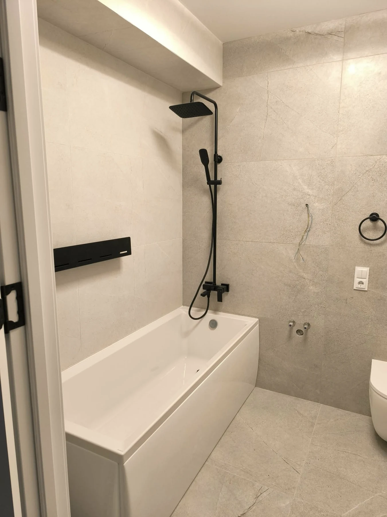 Tiled bathroom with bath and black shower fittings